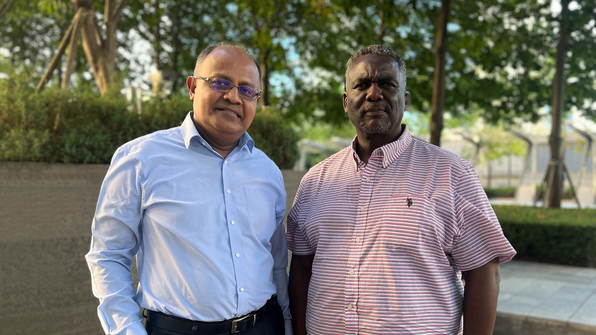 Ivor Poobalan and Victor Nakah stand outside in front of trees and the building where Lausanne was held in 2024