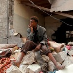 A Yemeni man sits amid the rubble of his family house that is damaged by an air-strike
