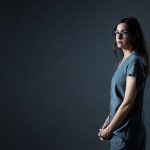 Donna Freitas standing in front of a dark background slightly in shadow