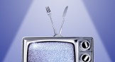 An old TV with a fuzzy screen and an antenna made from a fork and knife.