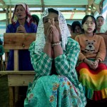 Children and their parents praying in a temporary church at a camp for internally displaced people in Myanmar.