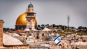 The Minaret and Golden Dome of the Al-Aqsa Mosquein in Jerusalem close to the Western Wall with an Israeli Flag on a rooftop