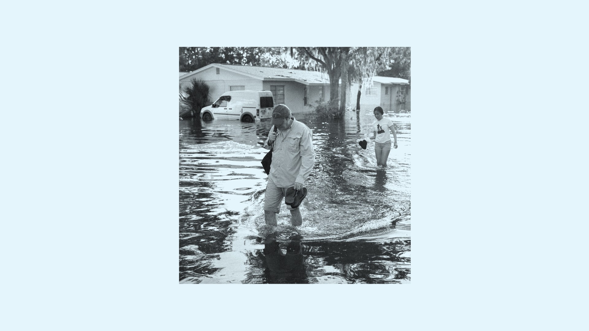 A man and woman walking through water left from the Hurricane Helene