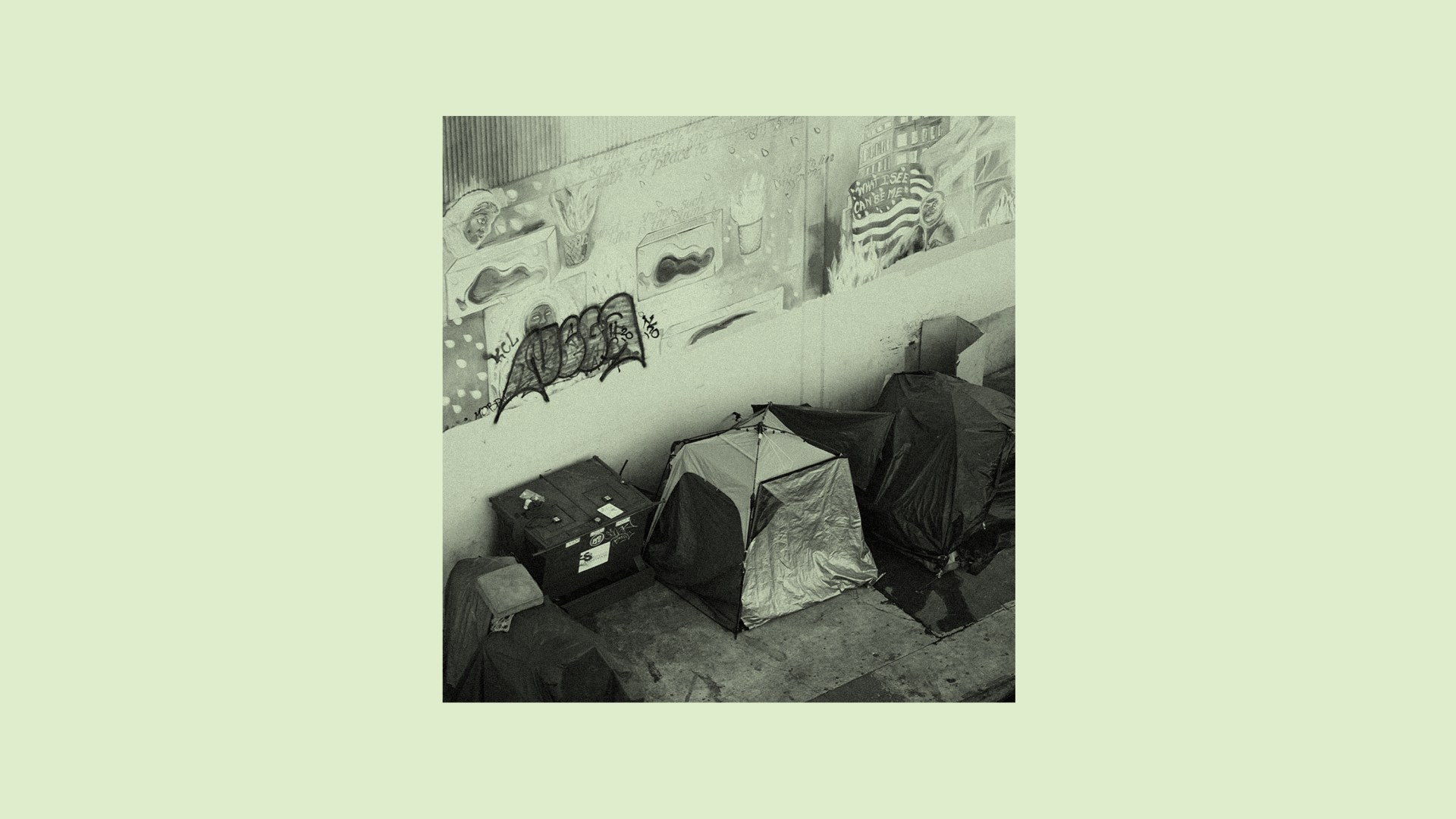 Tents near a garbage against a wall of graffiti