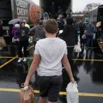 Boy carries plastic bags of food to a row of trucks at collection site.