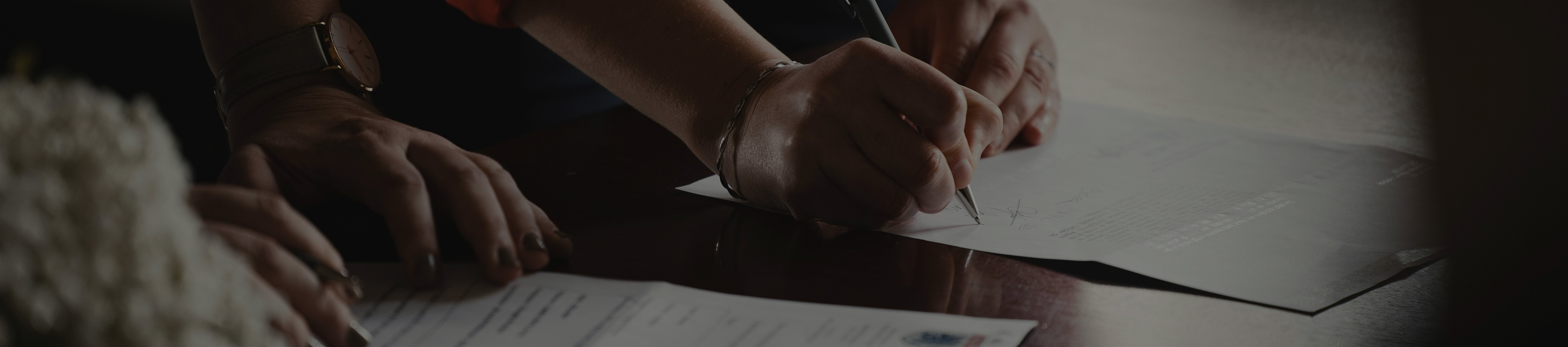 A close-up photo of a hand writing on a document