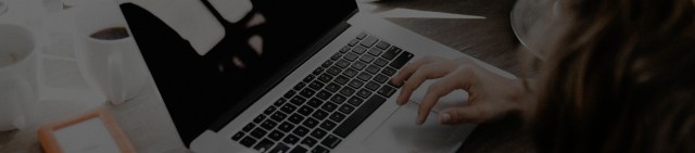 A close-up photo of a woman's hand on a laptop's keyboard