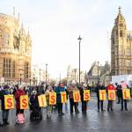 Supporters of the "Not Dead Yet" campaign, which opposes the Assisted Dying Bill, protest outside the Houses of Parliament in London, holding signs that spell out #ASSISTUSTOLIVE.