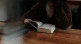 Woman turns the pages of a Bible on a table