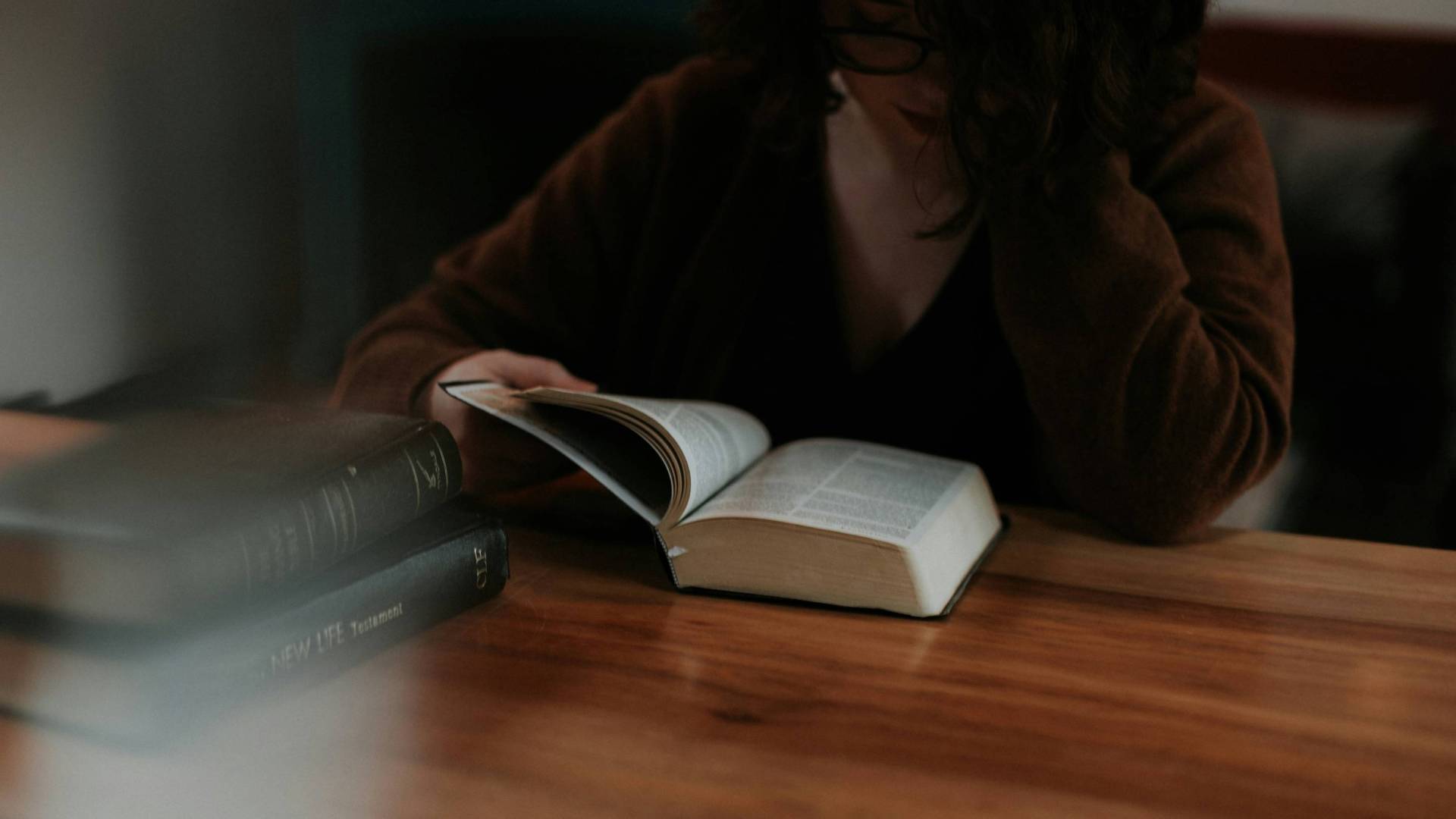 Woman turns the pages of a Bible on a table