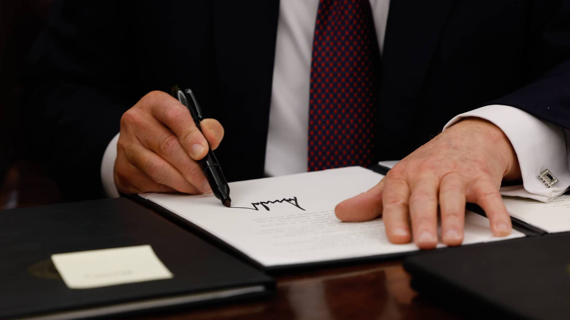 Trump signs executive order with a marker