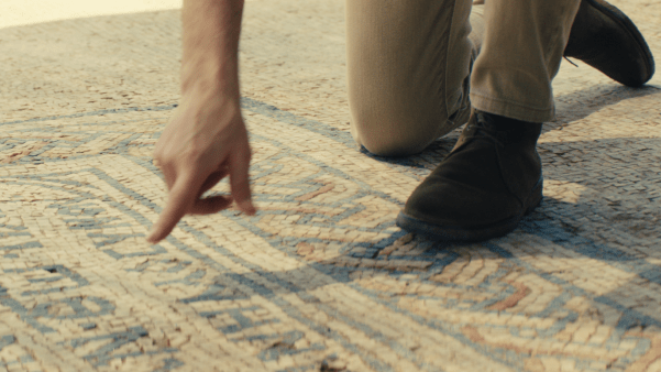 Man points at detail on Megiddo Mosaic, a church floor excavated by archaeologists
