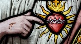 Close up of a stained glass window. Jesus pointing to sacred heart.