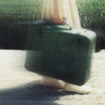A blurry image of a woman carrying a suitcase.