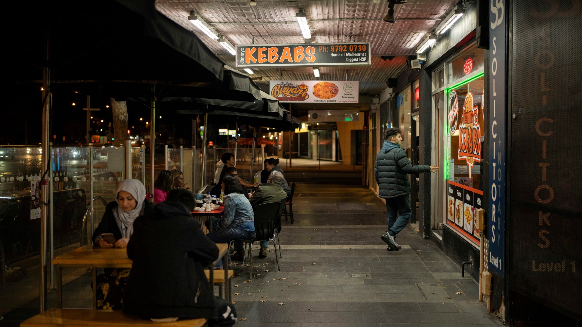 Mridula Amin Restaurant goers sit in a Main Street in Dandenong, a southeastern suburb of Melbourne, at night.