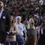 Lone woman in a crowd raises her hand.
