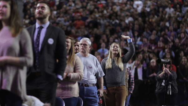 Lone woman in a crowd raises her hand.