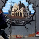 A man walks past graffiti on the Bethlehem side of the Separation Wall supporting the reconstruction of the Gaza Strip.