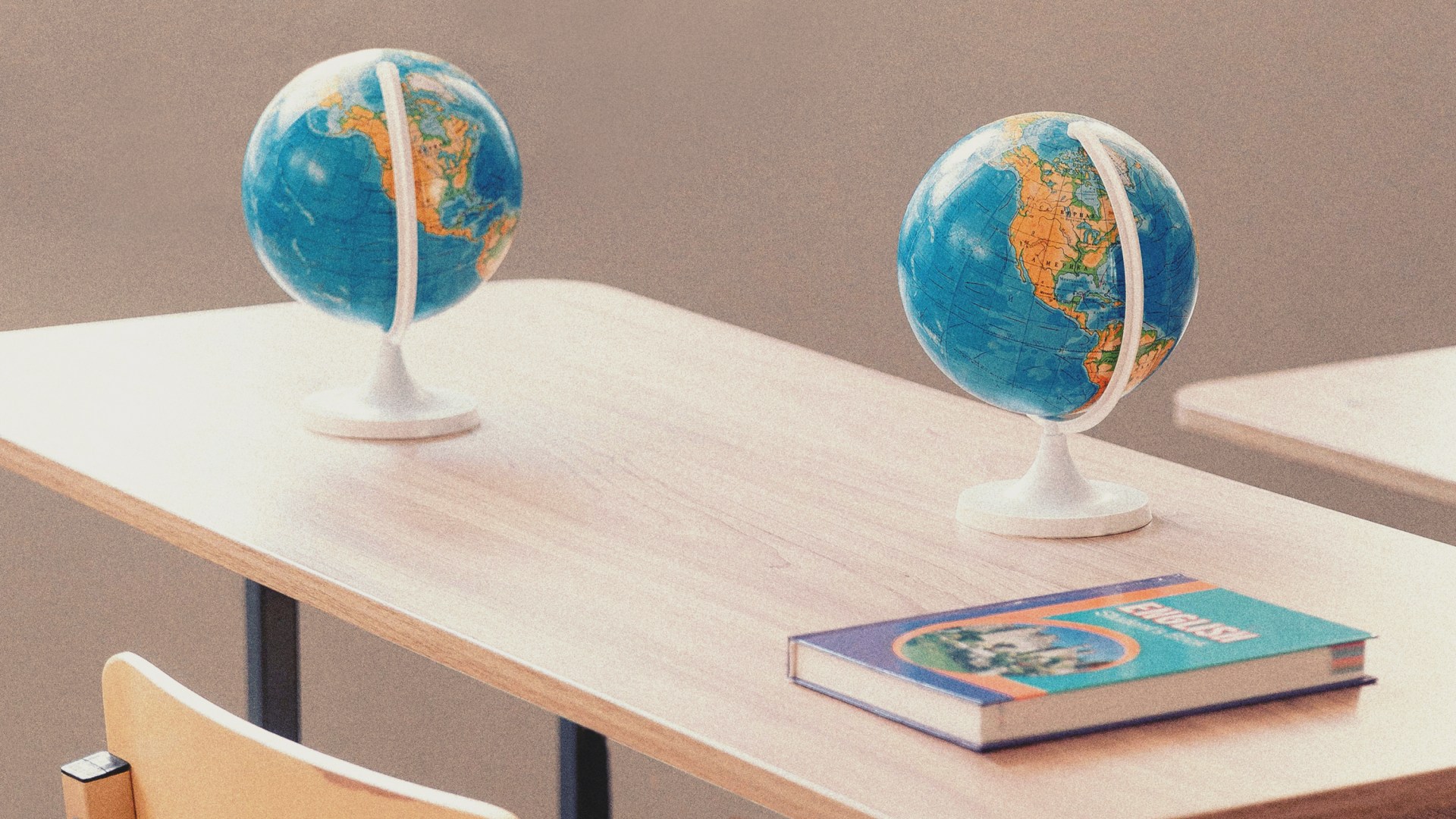 Two globes on a desk with an English text book on it