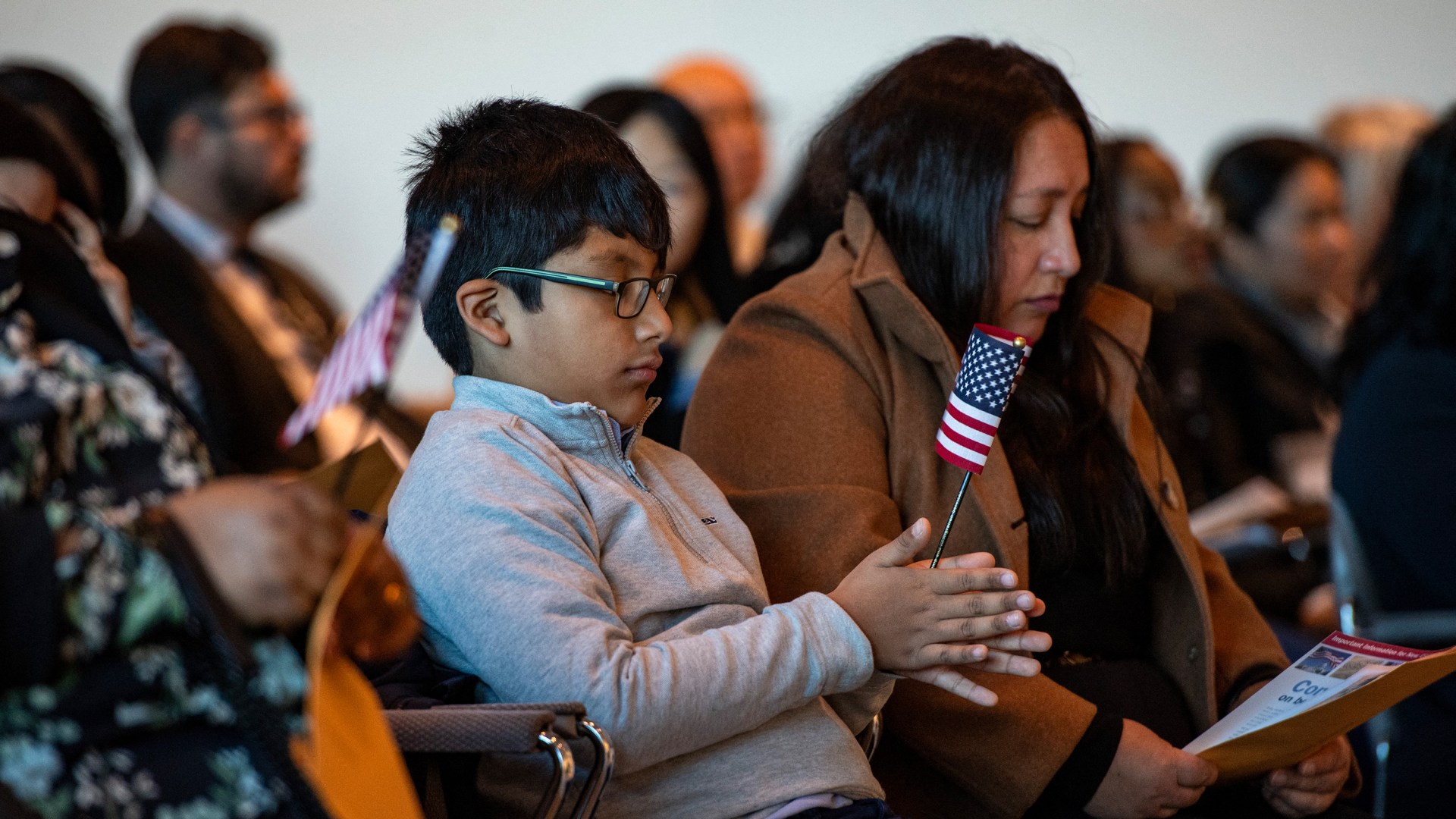 A child holds a US flag during a naturalization ceremony