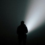Man standing in the dark with a beam of light.
