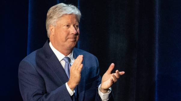 Robert Morris wears a navy suit and claps on stage.