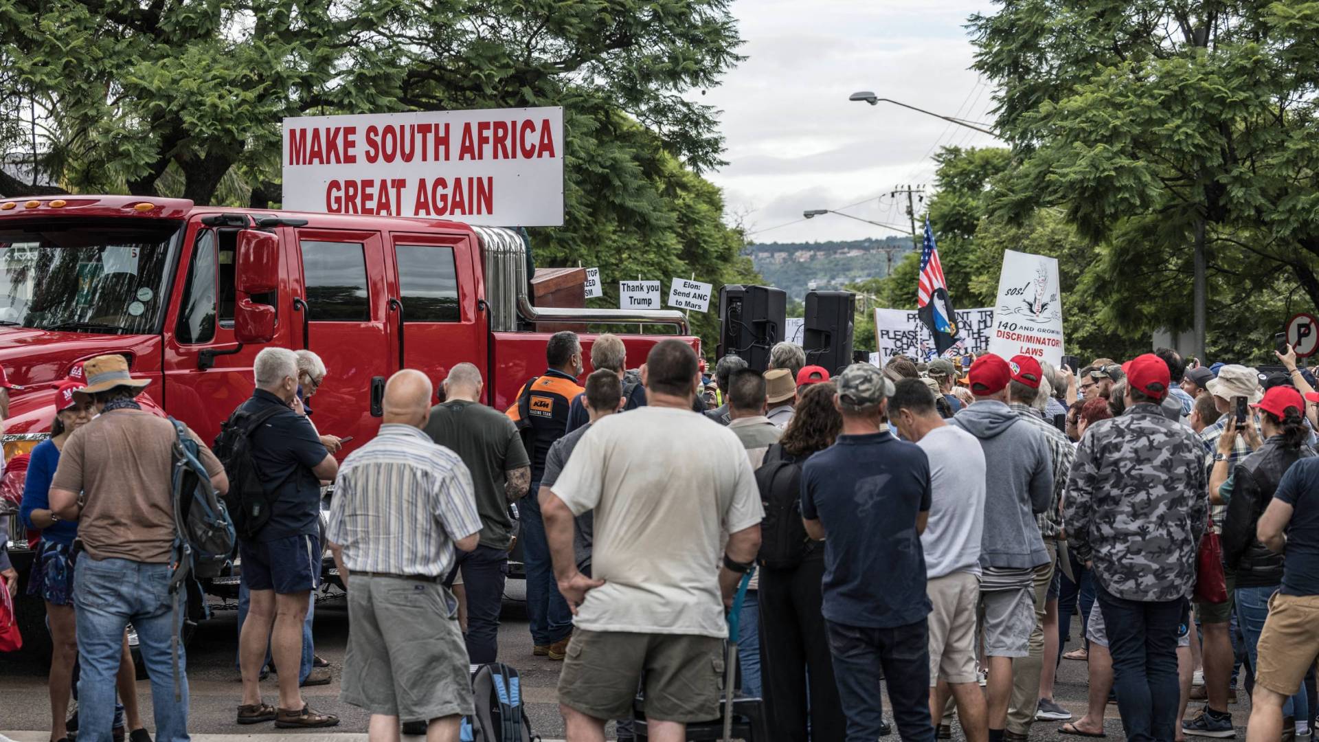 A group of South Africans in Pretoria demonstrate in front of a sign saying Make South Africa Great Again