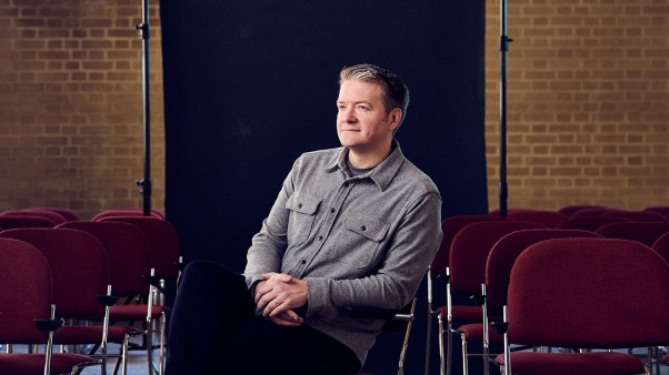 Portrait of Justin Brierley in a church with an exposed black backdrop behind