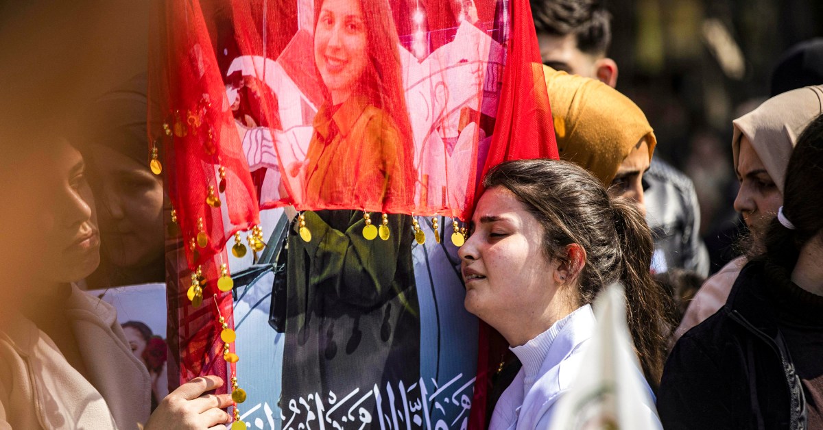 A woman reacts next to one of the pictures of victims of a recent wave of sectarian violence targeting Syria's Alawite minority.