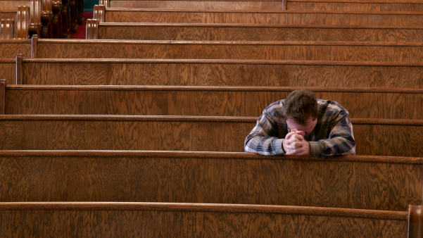 Middle age white man with head down in the pews