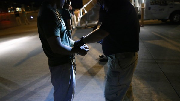 Undocumented immigrants are shackled before boarding an ICE charter jet.