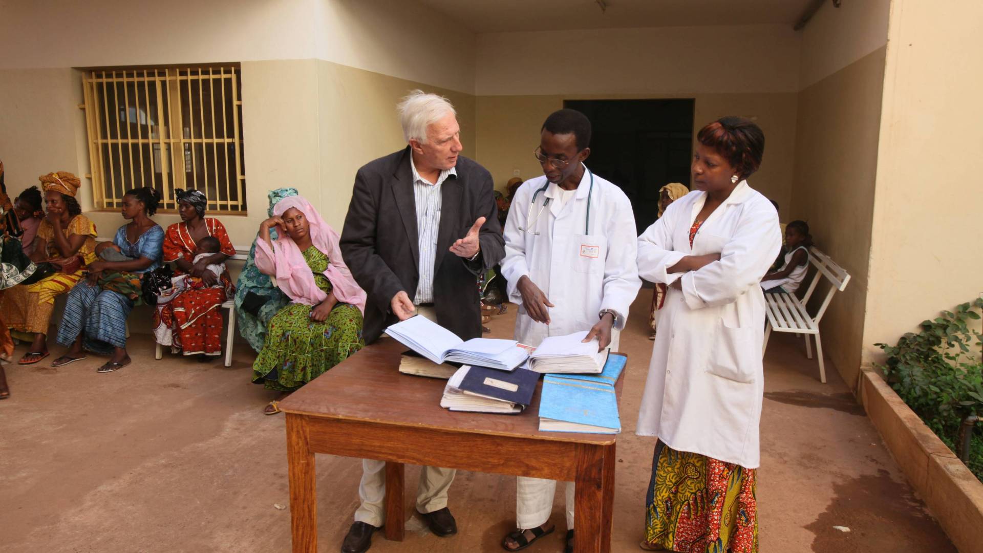 A white man consults with two African doctors at a clinic in Mali.