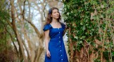 Nina Maksimova standing in a magical forrest wearing a blue dress.