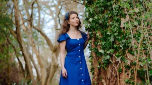 Nina Maksimova standing in a magical forrest wearing a blue dress.