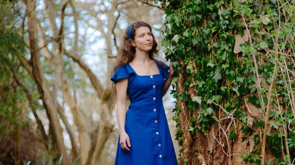 Nina Maksimova standing in a magical forrest wearing a blue dress.