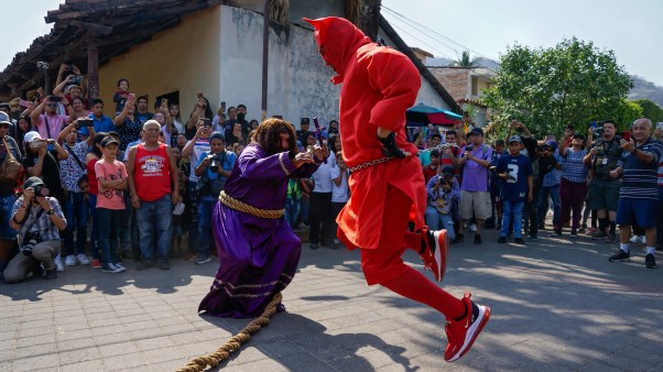 Salvadorans dressed as "Talcigüín" and Jesus dance during the tradition of Los Talcigüines in Texistepeque.