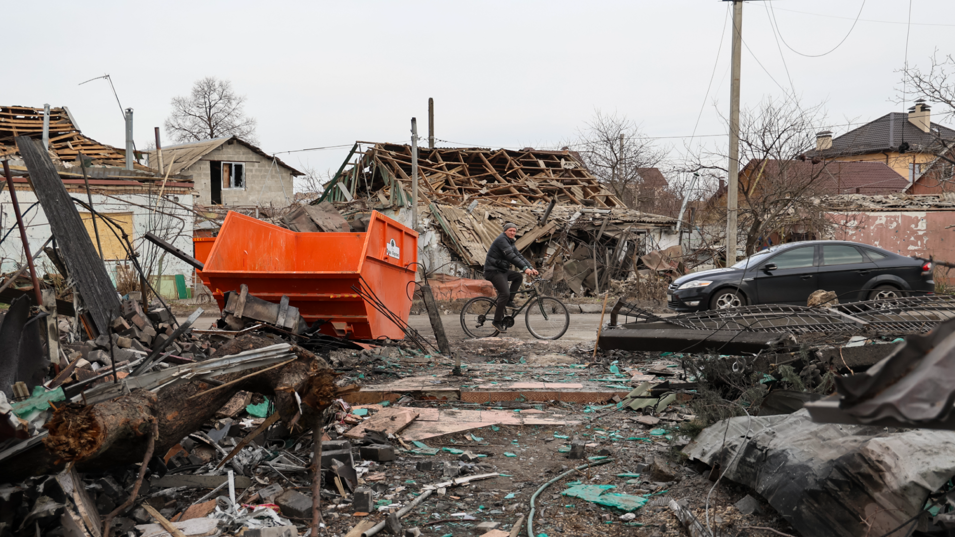 A man in Kherson Ukraine rides a bicycle through wreckage from Russian bombs