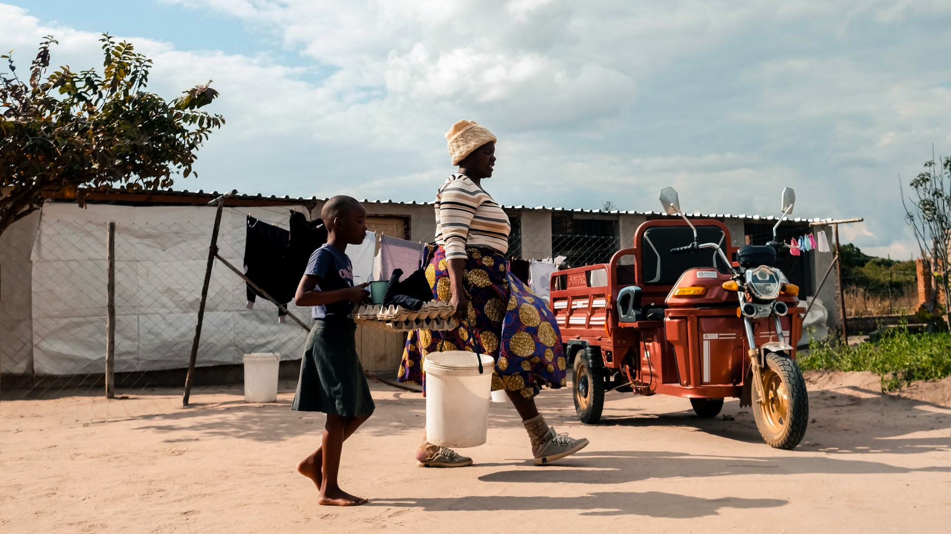 A poultry farmer in Zimbabwe prepares to go to market on her renewable energy electrical tricycle.