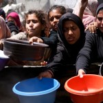 Displaced Palestinians gather to collect portions of cooked food at a charity distribution point in Gaza.
