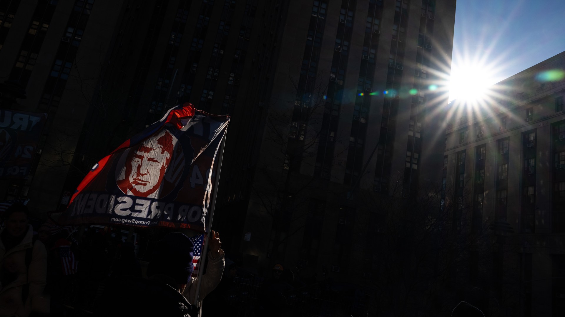 A supporter holds up a flag of Donald Trump.