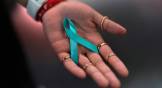 An open hand holds a turquoise memorial ribbon loop