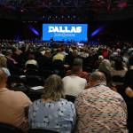 Crowd in convention center with three screens.