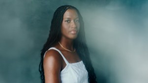Headshot of Adira Polite on blue background with light obscuring her face