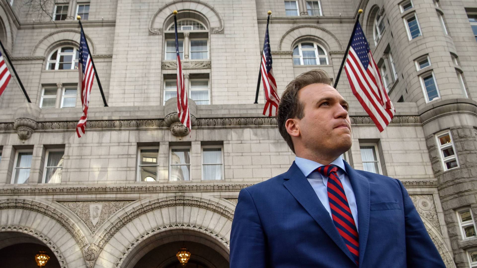 Johnnie Moore in blue suit in front of Trump building with American flags