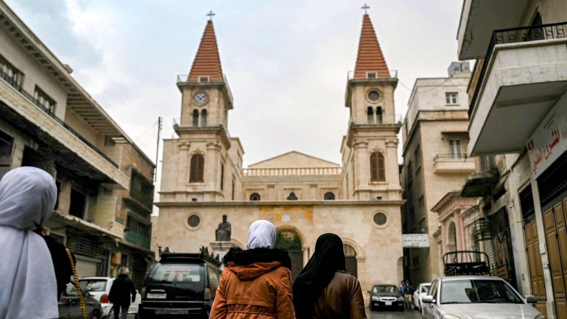 Muslim women walk near a church in Syria