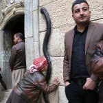 A Yazidi boy kisses a figure of a black snake at the entrance of the Temple of Lalish in Iraq.