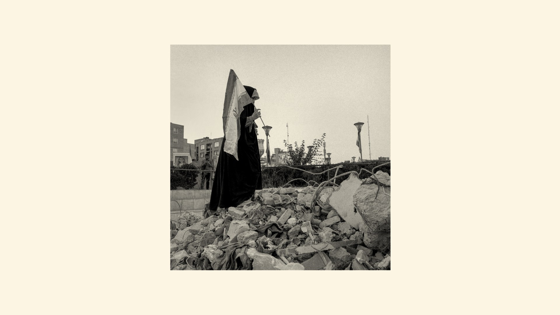 A woman standing in rubble with an Iranian flag.