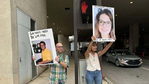 Two demonstrators hold posters with faces of SBC abuse victims including Jennifer Lyell.