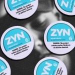 Several containers of Zyn sitting on top of a photo of a depressed young man.