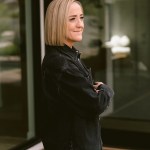 Photograph of Christine Caine standing in a black jacket with arms crossed outside of a modern house.